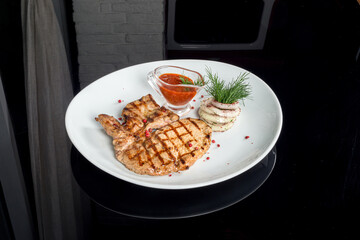Grilled pork served with sauce on a white plate