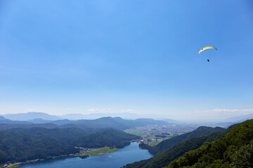Fototapeta na wymiar 夏、木崎湖上空を飛ぶパラグライダー 長野県 大町市