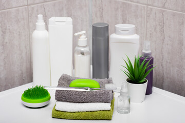 Fototapeta na wymiar Bottles of soap and shampoo and cotton towels with green plant on a white table against the background of a bathroom.
