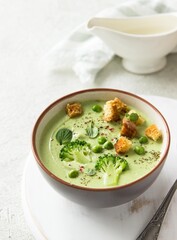 Summer cream soup with green fresh pea shoots. Top view. Green vegetable cream soup in a white bowl...