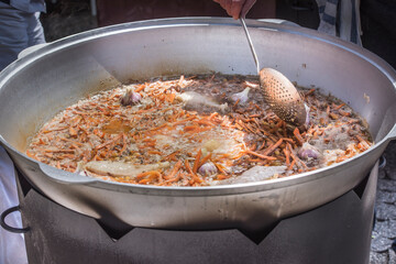 The preparation of traditional Uzbek pilaf with meat, carrots, garlic and spices