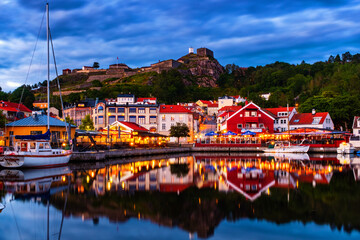 Halden, Norway. View of the illuminated houses and yachts with Fredriksted fortress at the background in Halden, Norway in the evening with cloudy sunset sky in summer