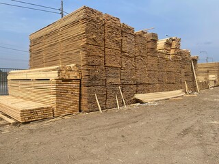 Wooden boards, lumber, industrial wood, timber. Pine wood timber stack of natural rough wooden boards on building site. Industrial timber building materials