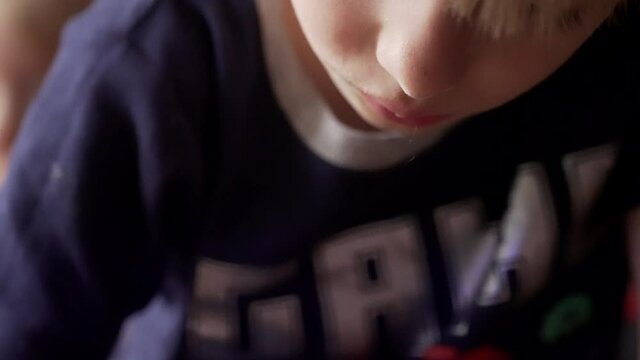 Close-up portrait of a little boy coloring a picture.