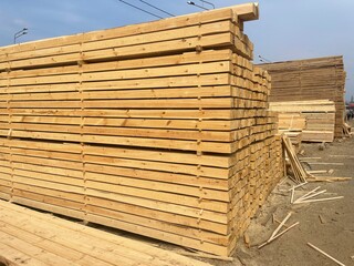 Wooden boards, lumber, industrial wood, timber. Pine wood timber stack of natural rough wooden boards on building site. Industrial timber building materials