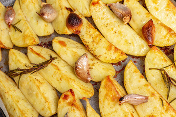 Baked pieces of spiced potato in a baking pan