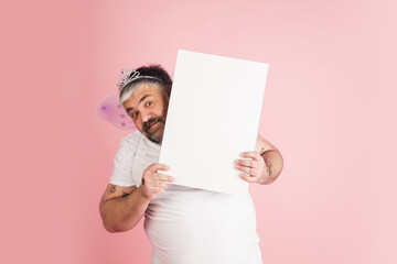 Handsome caucasian plus size male model isolated on coral pink studio background. Concept of inclusion, human emotions, facial expression