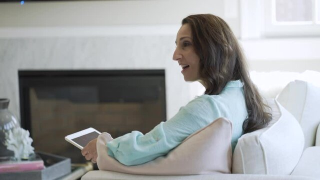 Smiling woman talking to someone while using her digital tablet