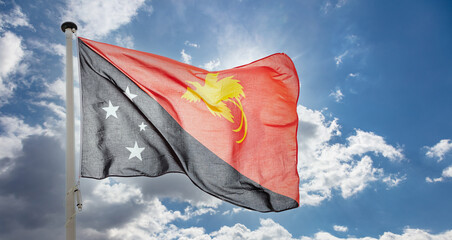 Papua New Guinea flag waving against blue cloudy sky