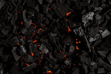 Black charcoal with red streaks of heat. Black textured background.