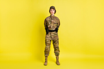 Full body photo of pretty focused person standing hold hands behind back isolated on yellow color background