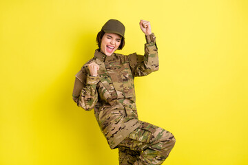 Portrait of delighted positive lady closed eyes fists knee up open mouth shout yes isolated on yellow color background