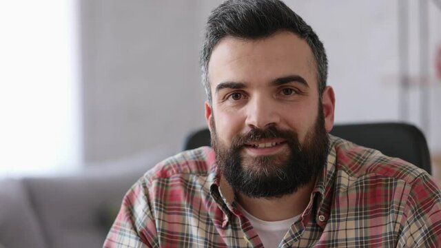 Portrait of confident handsome bearded man looking at camera. Front close up portrait of smiling Caucasian adult man. Beautiful human face.