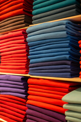 Vertical photo of clothes folded and sorted by colour ranges