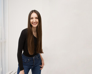 Smiling brunette on white background Dressed in a black T-shirt and jeans