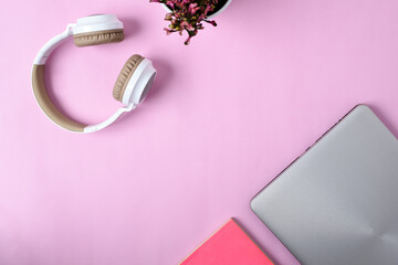 Fototapeta na wymiar Top View Flatlay of modern wireless headphone, minimalist laptop, Cute purple Flower, and book