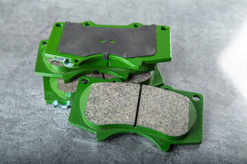 a set of new green brake pads on a gray table