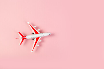 toy Model of a modern airplane with red wings. tourism and travel concept. pink background top view