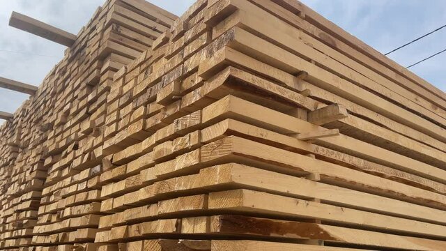 Wooden boards, lumber, industrial wood, timber. Pine wood timber stack of natural rough wooden boards on building site. Industrial timber building materials