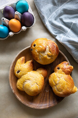 Sweet brioche dough in the shape of Easter bunnies, and an egg carton with colored Easter eggs.