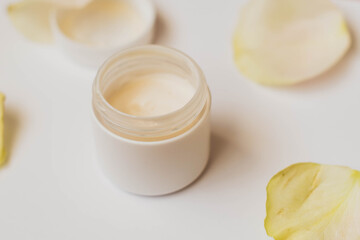 Bowl of cream wiht roses on white background, top view. image of homemade cosmetics ingredients. aroma theme. organic cosmetics.