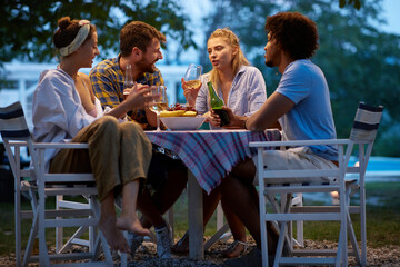multiethnic couples drinking beer and wine outdoor in the evening, socializing