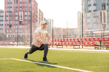 Fototapeta premium Sport. Fitness Girl Doing Stretching Workout. Fashion Sporty Woman With Strong Muscular Body Training. Fit Female Stretching At Outdoor Stadium.