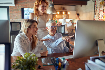 Two younger women colleagues being mentored by senior successful businesswoman