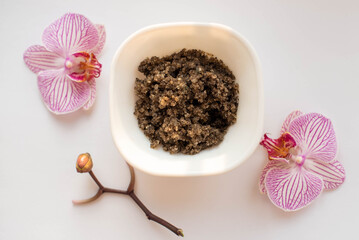 Plate of scrub wiht roses on white orcgids, top view. image of homemade cosmetics ingredients. aroma theme. organic cosmetics.