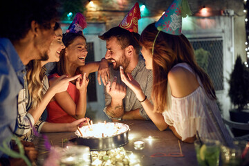Group of cheerful friends trying birthday cake at the open air party. Quality friendship time together