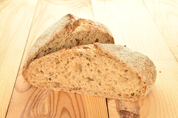 Two fresh halves of a loaf of bread, close-up, on a wooden table.
