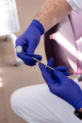 Dental mirror in male hands with blue medical gloves