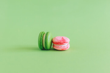 Tasty french macarons on a green pastel background.
