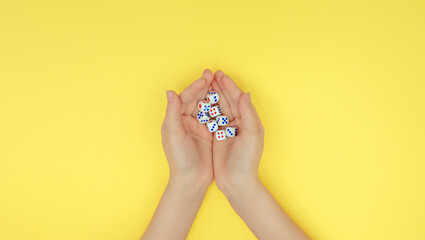 hands with dice on a yellow background