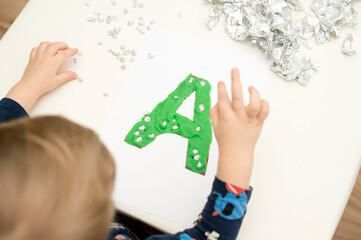 Two year boy decorating play dough letter 
