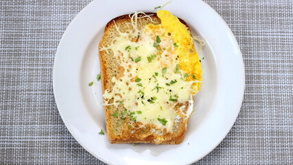 Hot sandwich with egg, cheese and herbs on a plate.