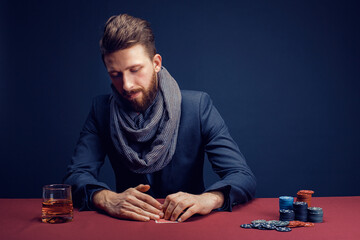 Stylish bearded Man playing in dark casino, smoking cigar, drink whiskey