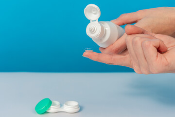 The girl on her finger holds a contact lens and solution, next to the container.