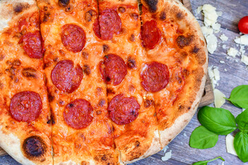 Home made italian  pepperoni   pizza with  tomatoes, mozzarella and parmesan cheese and fresh basil 