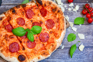 Home made italian  pepperoni   pizza with  tomatoes, mozzarella and parmesan cheese and fresh basil 