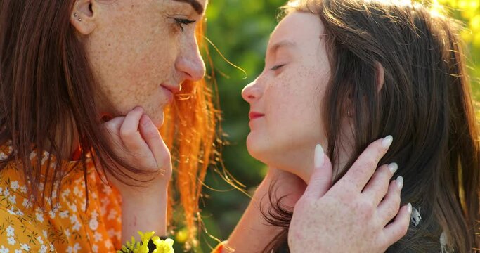 redhead mom with her daughter. little girl strokes momy hand. freckles on the face of mom and daughter.