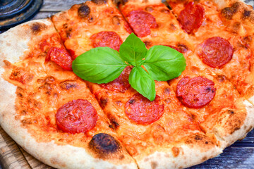 Home made italian  pepperoni   pizza with  tomatoes, mozzarella and parmesan cheese and fresh basil 