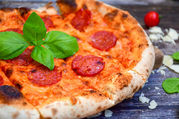 Home made italian  pepperoni   pizza with  tomatoes, mozzarella and parmesan cheese and fresh basil 