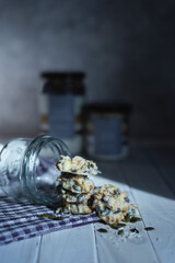 white chocolate Coconut and seeds home made cookies in glass jar on white wooden table in sun light