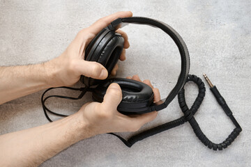 Male hands holding vintage stereo headphones against a gray background, top view