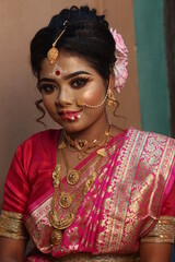 Portrait of an beautiful woman Indian model in Bridal look with heavy gold jewelry and red sari.