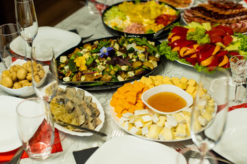 Glasses goblets on white table. Room with table serving fruits and dishes and meal. cheese, honey, salads, snacks.