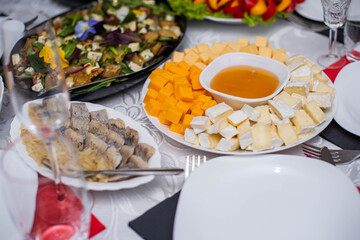 Glasses goblets on white table. Room with table serving fruits and dishes and meal. cheese, honey, salads, snacks.