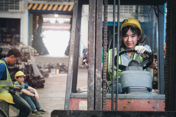 Fototapeta na wymiar Industrial worker woman wearing helmet driving forklift car at manufacturing plant factory industry, Asian beautiful female engineer and many engine parts as blurred background