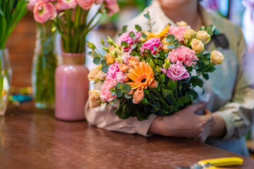 Florist holding a bouquet of fresh flowers bouquet in a flower shop. The master decorator creates a bouquet for a flower arrangement for the celebration